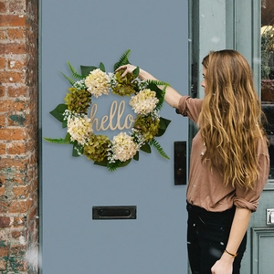 Detail of a decorative hydrangea wreath with a wooden hello sign on a blue front door