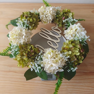 Detail of white hydrangea wreath with green fern leaves and wooden Hello sign decoration