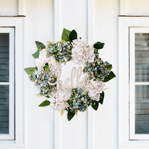 Detail of hello wooden sign on hydrangea floral wreath with green leaves decor