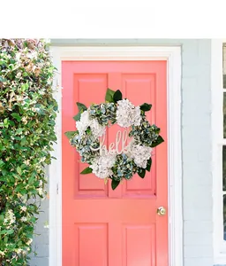 Detail of wooden hello sign on white and blue hydrangea wreath on pink door