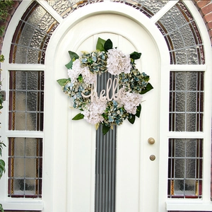 Detailed view of artificial hydrangea wreath with green leaves and a wooden hello sign