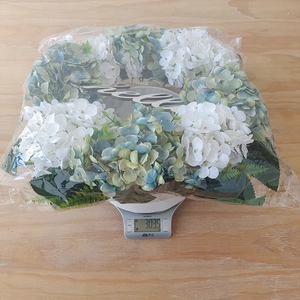 Weight measurement of hydrangea wreath with hello sign showing 303.5g on a scale