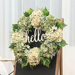 Artificial hydrangea wreath with green leaves and wooden hello sign on rustic dark wood