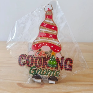 Detail of wooden cooking gnome ornament featuring festive red and black plaid and snowflakes