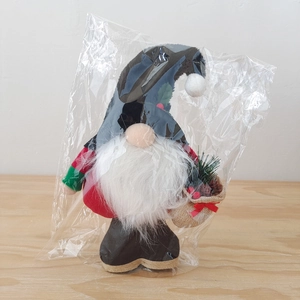 Detalle de un gnomo de Navidad con gorro negro y saco en embalaje de plástico transparente