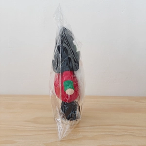 Detalle del gnomo de Navidad de peluche rojo envuelto en una bolsa plástica protectora