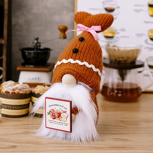 Detail of knitted gingerbread gnome holding a wooden Gingerbread Cafe sign with coffee decor