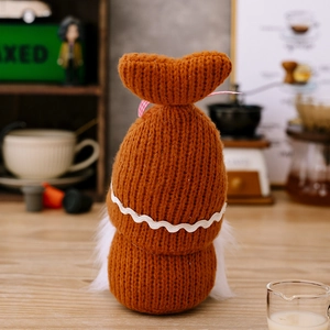 Detail of a handmade coffee gnome plush featuring brown knitted texture and long white fur