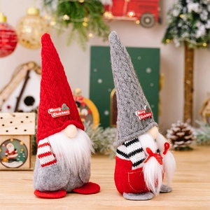 Close-up of two Christmas gnomes with knit pointed hats and long white beards on wood
