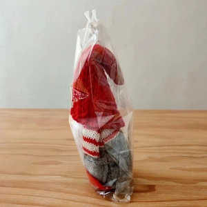 Christmas gnome plush toy in red knitted hat and striped scarf, sealed in clear packaging