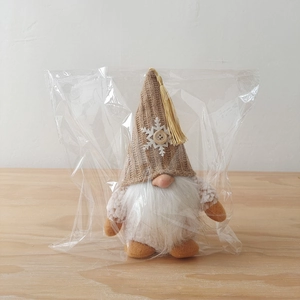 Detail of Christmas gnome plush with brown knit hat, snowflake patch, and white beard