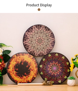 Three bohemian shaman drums with colorful patterns and a furry mallet on a wooden table