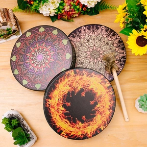 Bohemian shaman frame drums with mandala patterns and wooden mallet on a floral desk