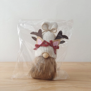 Close-up of a Christmas gnome featuring knitted shell antlers and red plaid ribbon bows