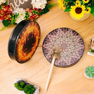Detail view of Shaman hand drums with mandala patterns and wooden drumstick on table