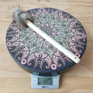 Detail showing the lightweight 227.5g shaman drum with decorative mallet on a scale