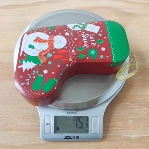 Detailed view of snowman Christmas stocking tin box on a digital scale weighing 75.1g