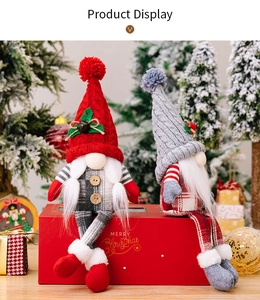 Detail of two Nordic Christmas gnomes with knit hats and bells on a red gift box