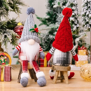 Detail of two Nordic Christmas gnomes with knitted hats and plaid outfits on a wooden stool