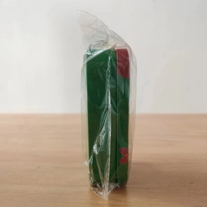 Detailed view of rectangular green tin gift box with red petal pattern in packaging