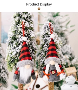 Close-up of red and black checkered Christmas gnomes with wooden buttons on a snowy tree
