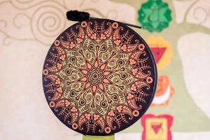 Close-up of mandala shaman drum with intricate patterns and black plush mallet