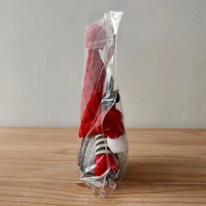 Close-up of Nordic Christmas gnome plush with red knitted hat and striped long legs