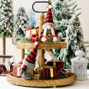 Christmas gnomes with red and black plaid hats and glowing lights on a wooden tray