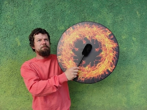 Detail of printed shamanic frame drum with flame pattern and black mallet accessory