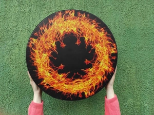 Detail of bohemian shaman drum with orange fire flame pattern held by hands