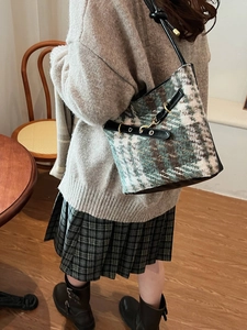 Sac seau rétro en tweed à carreaux avec anneau doré porté par un mannequin en intérieur