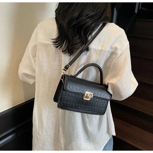 Detailed view of the black crocodile pattern leather crossbody bag worn by a model