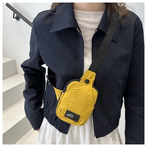 Detail of a bright yellow nylon chest bag featuring a black strap and front buckle pocket
