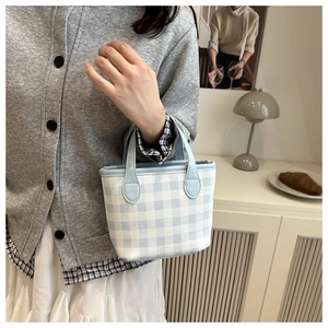 Detail of light blue gingham handbag showing the textured fabric and leather handles