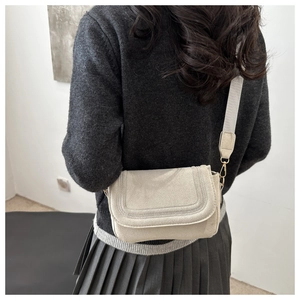 Detail of cream saddle bag with U-shaped stitching and wide strap on model