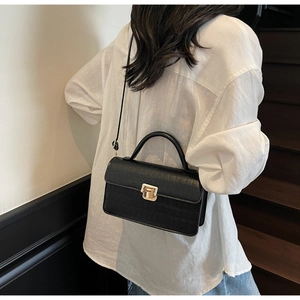 Detail view of black crocodile pattern crossbody bag with vintage gold twist lock buckle