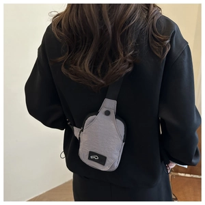 Detail of grey lightweight nylon chest bag with black adjustable strap on black hoodie