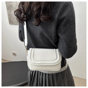 Detail of white PU leather crossbody bag with curved quilting and gold metal hooks