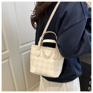Detail of checkered canvas mini tote showing cylinder handles and adjustable strap