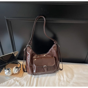 Close-up of brown patent leather hobo bag with vintage silver buckle and front pocket