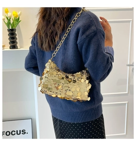 Detail of a chic gold sequin underarm bag with a glossy metallic chain strap