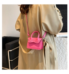 Detailed view of magenta PU leather mini bag with litchi texture on beige trench coat