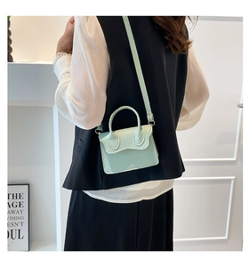Détail d'un petit sac vert menthe montrant la texture cuir grainé et la poignée