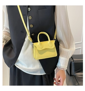 Petit sac à main jaune en cuir avec poignée et bandoulière porté à l'épaule