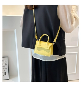 Detail of bright yellow mini leather bag with pebble texture and crossbody strap