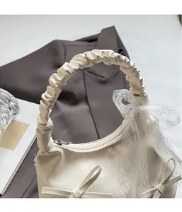 Detail of creamy white handbag with cloud ruffle handle and lace bow accents