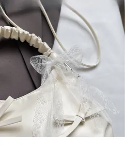 Close-up of white pleated hobo bag featuring delicate lace bow and textured handle