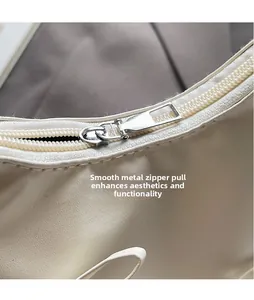 Detail of sleek silver metal zipper pull on off-white pleated cloud handbag