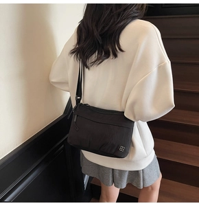 Rear view of model wearing minimalist black crossbody bag on a wooden staircase