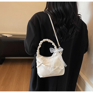 Detail of cream white pleated shoulder bag with lace bowknot and soft PU texture